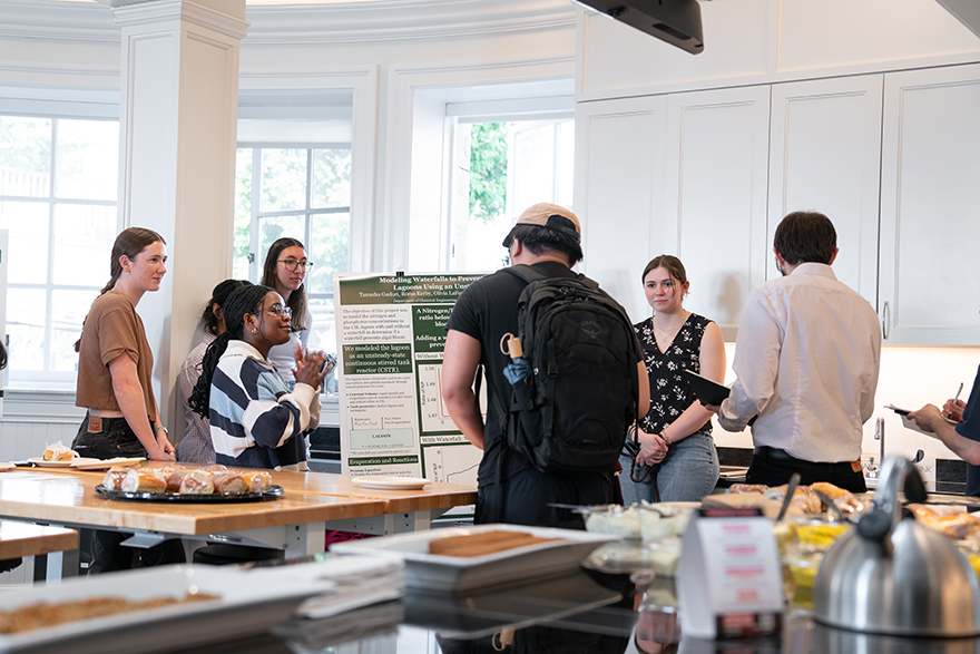 Seven students standing around a project poster