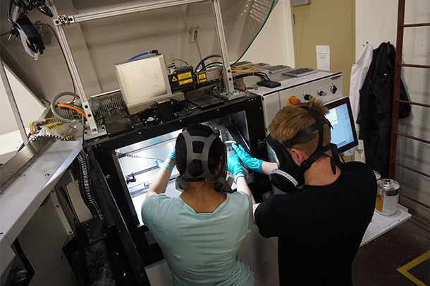 Two students adding powders to a 3D printer